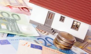 Piccola casa con banconote e monete in euro